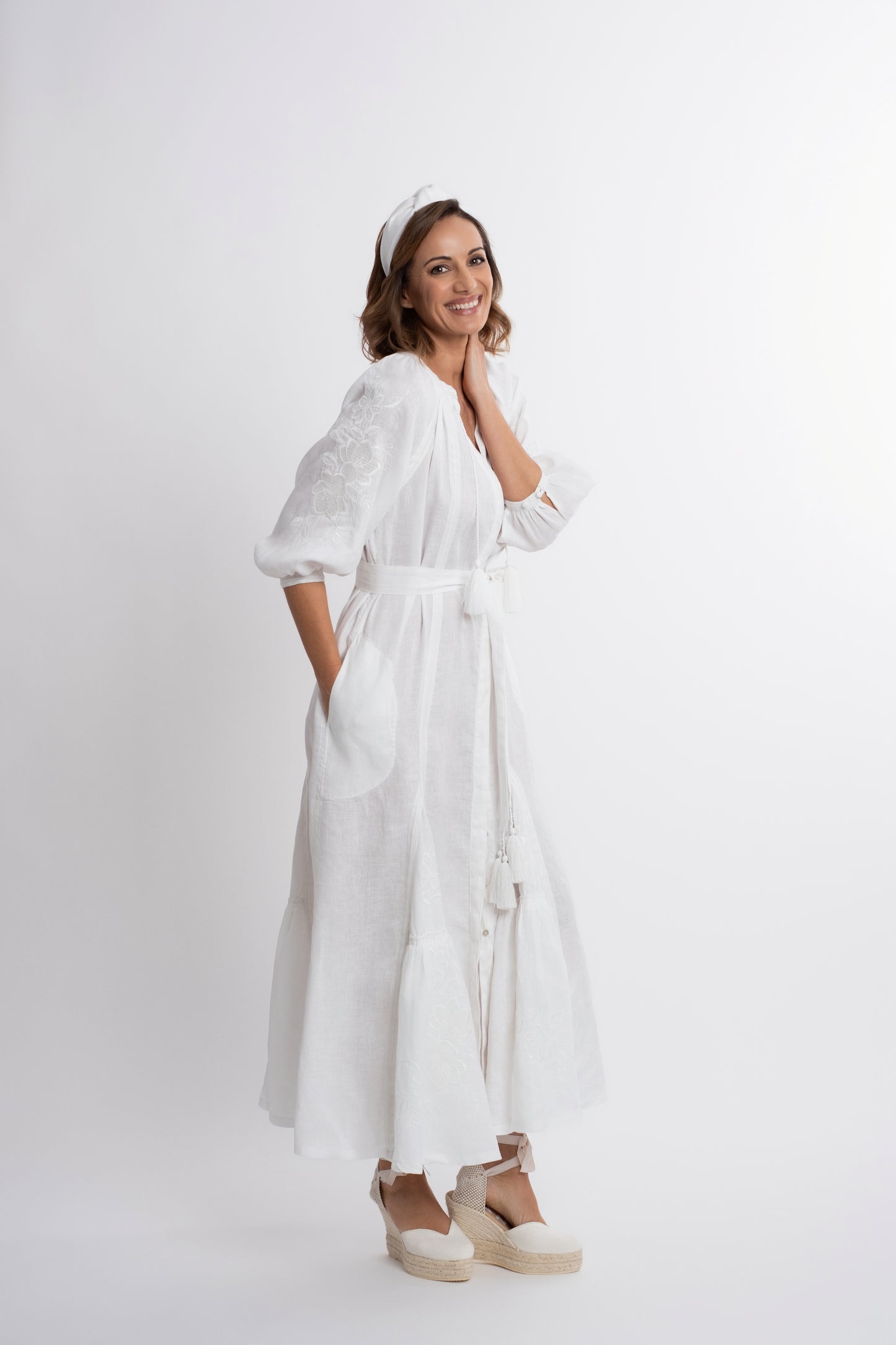 Ibiza: Vestido de lino blanco bordado con cinturón, pompones y botones de nácar.