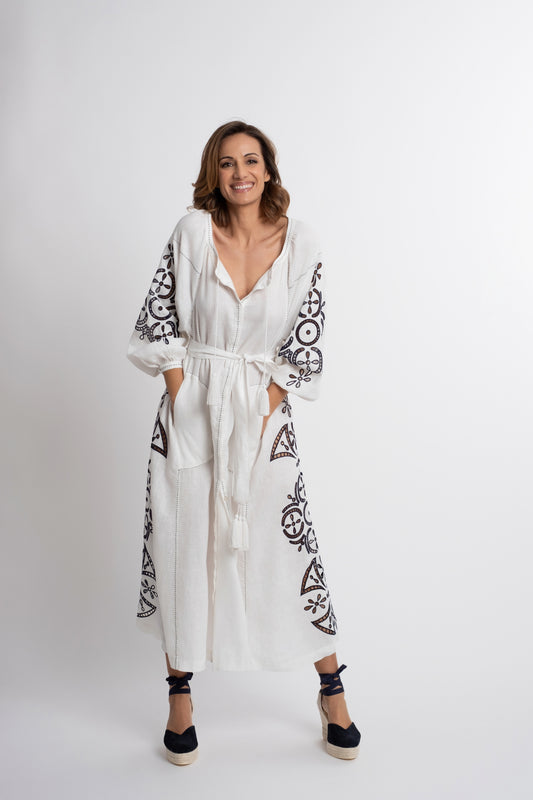 Santorini: Vestido de lino blanco con cinturón, bordado en azul marino con pompones y botones de nácar.