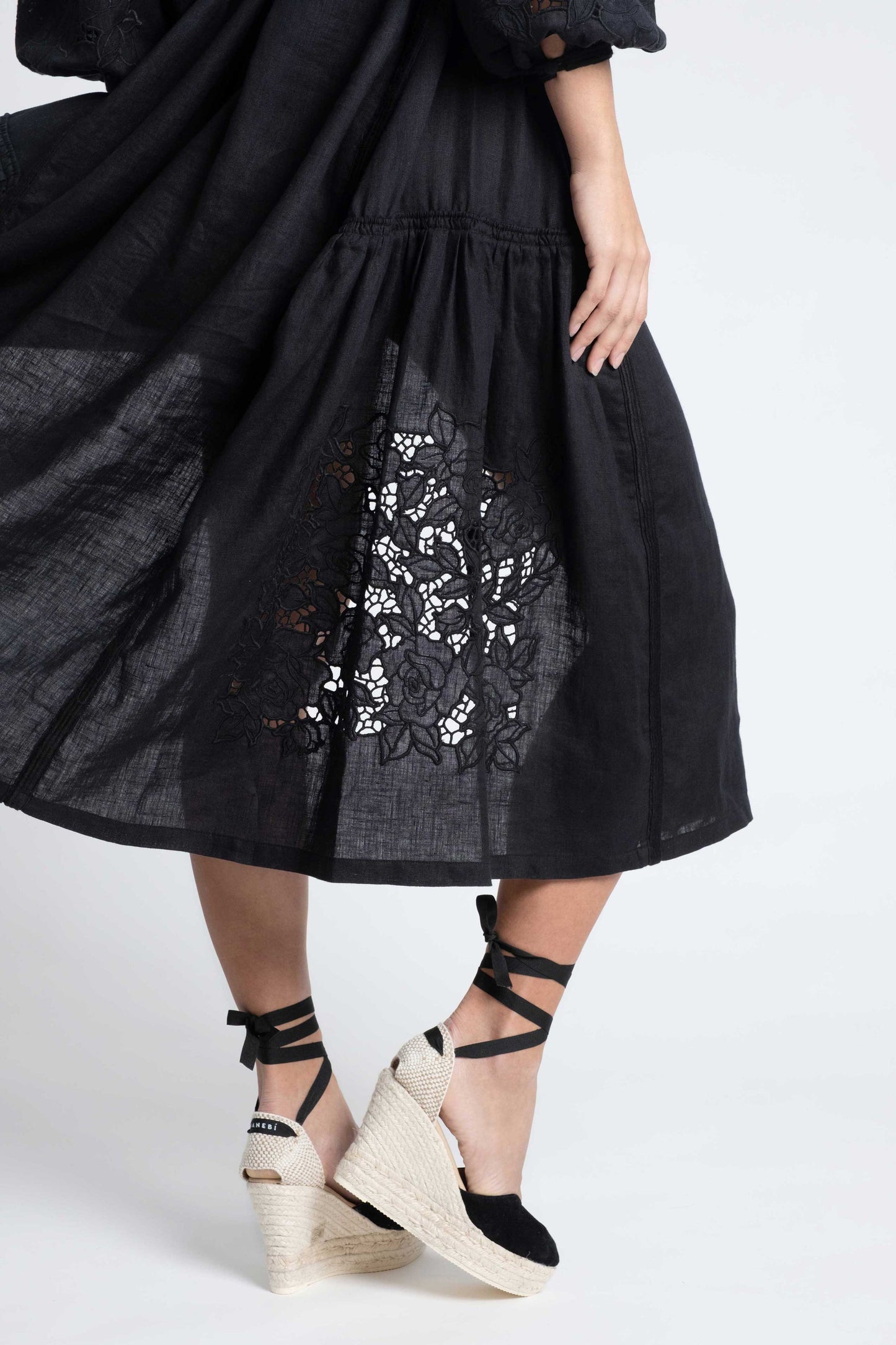 Capri: Vestido de lino negro con bordado suizo, pompones y botones de nácar.