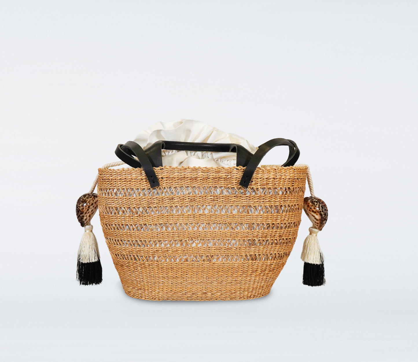 Milos: Small black basket in straw, black recycled leather handles, cotton bag and natural shells.