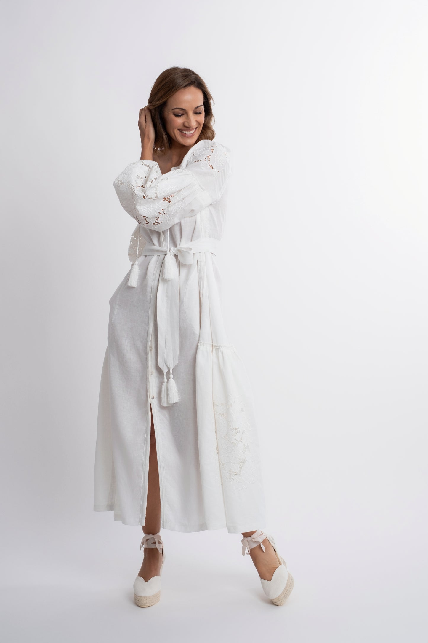 Capri: Vestido de lino blanco con cinturón, bordado suizo con pompones y botones de nácar.