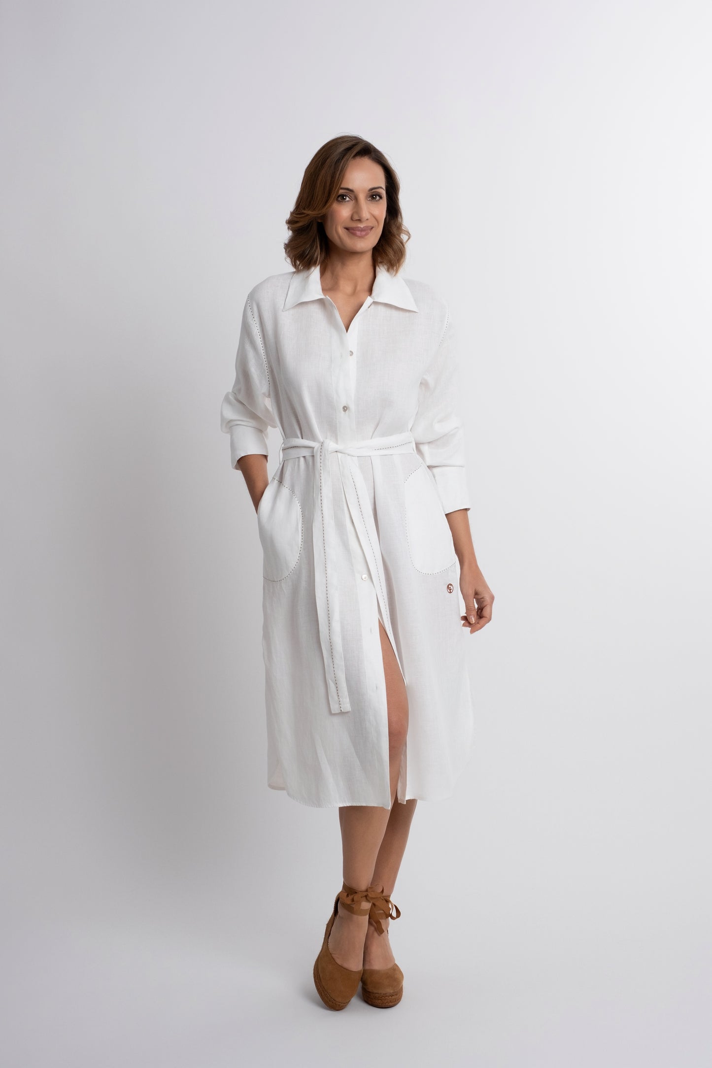 Dubai: white linen shirt belted dress with contrasting topstitch embroidery and mother of pearl buttons.