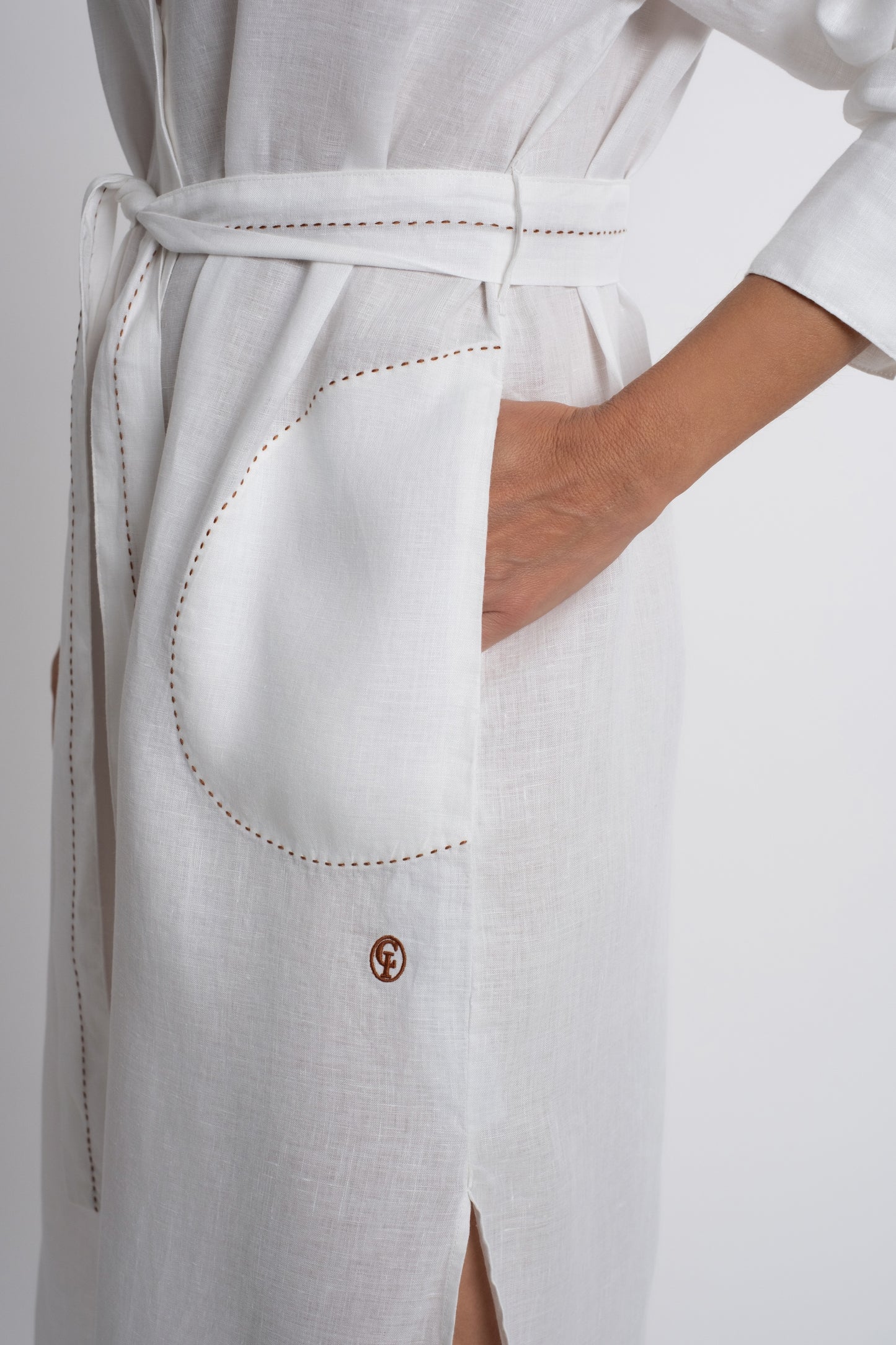 Dubai: white linen shirt belted dress with contrasting topstitch embroidery and mother of pearl buttons.