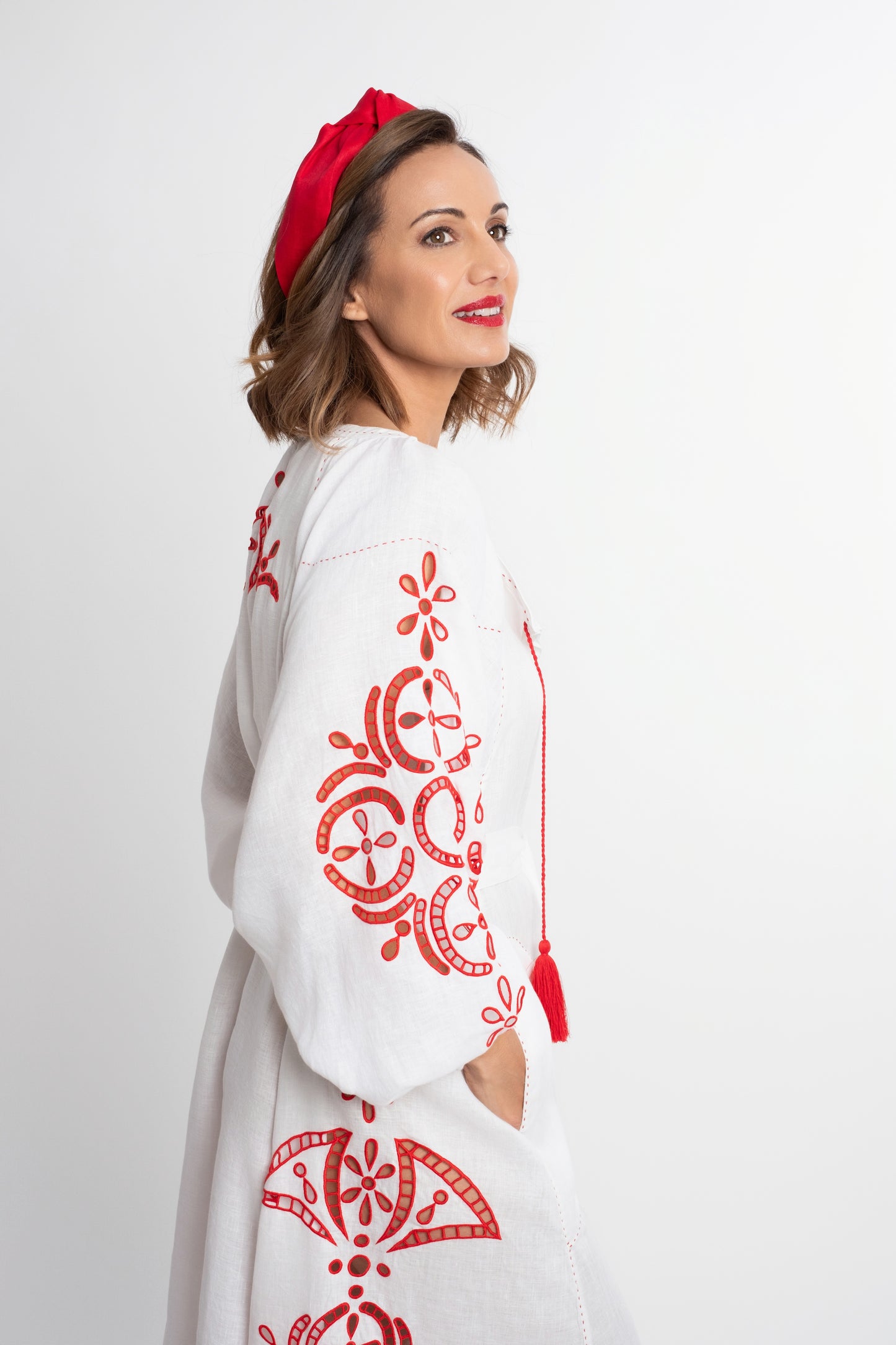Santorini: Vestido de lino blanco con cinturón, bordado en rojo con pompones y botones de nácar.