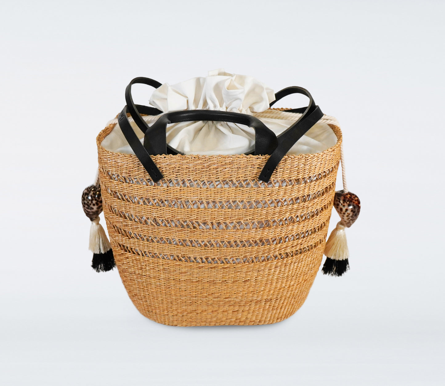 Large black basket in straw, black recycled leather handles, cotton bag and natural shells.